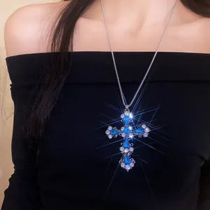 Détail d'un collier pendentif croix en strass bleu étincelant porté par un mannequin