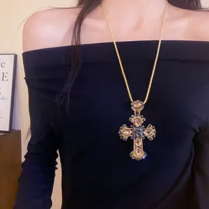 Vue détaillée d'un collier pendentif croix doré orné de cristaux étincelants incrustés