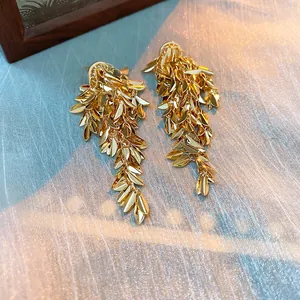 Primo piano di orecchini a nappa in foglia d'oro con design metallico a foglia di grano