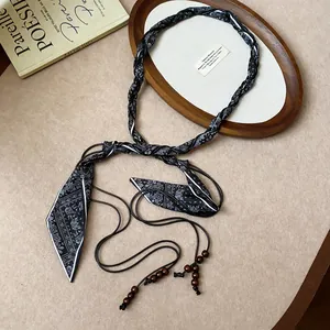 Detail of a woven silk scarf belt featuring dark wooden beads and paisley pattern
