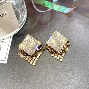 Vista dettagliata di orecchini a rombo color oro con strass scintillanti e nappe a maglia.
