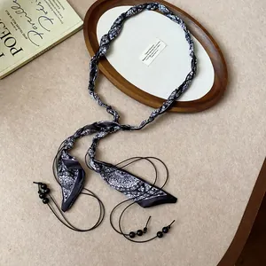 Detailed view of a minimalist woven silk scarf belt featuring black bead cord accents.