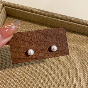Close-up shot of elegant round pearl stud earrings displayed on a rustic wooden board