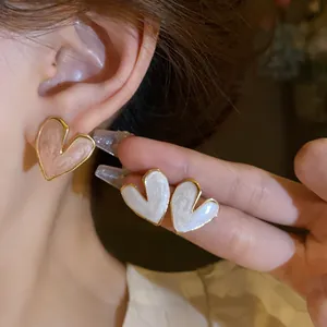 Detailed view of heart-shaped enamel stud earrings in pink and white colors