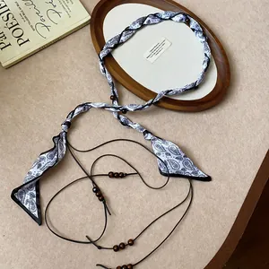 Close-up of paisley silk scarf braided waist chain with wooden bead accents