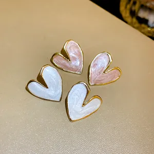 Close-up of pink and white heart-shaped enamel dripping oil stud earrings with gold edges
