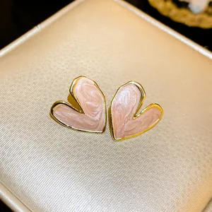 Close-up of pink enamel heart stud earrings with golden trim on a jewelry box