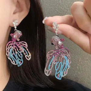 Dettaglio macro degli eleganti orecchini a pesce rosso con strass rosa e blu brillante