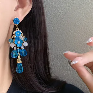 Vista dettagliata di elegante orecchino a fiori blu con cristalli e oro lucido