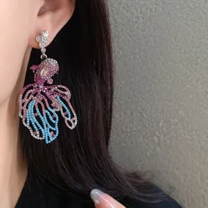 Primo piano di orecchini pendenti a forma di pesce rosso con strass luccicanti