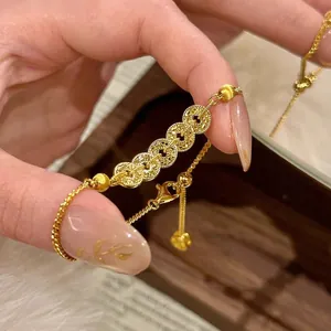 Gros plan du bracelet en pièces chinoises dorées avec une chaîne réglable élégante