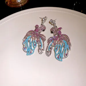 Primo piano dettagliato di orecchini a forma di pesce rosso con strass rosa e blu