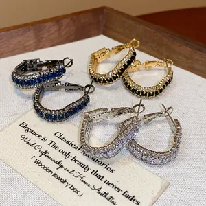 Detailed view of three pairs of geometric zircon hoop earrings in gold and silver tones.