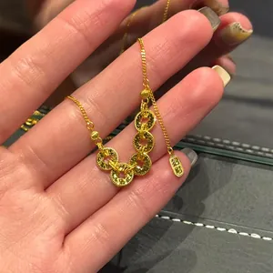 Gros plan d'un collier de pièces en cuivre doré avec cinq anneaux et plaque porte-bonheur