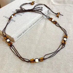 Detail of ethnic style woven waist chain with wooden and ceramic beads on linen