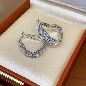 Close-up detail of geometric silver earrings with zircon inlay in a premium jewelry box