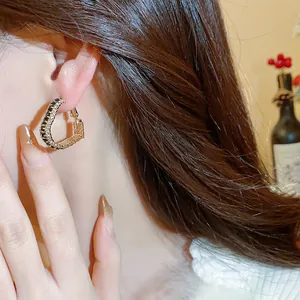 Close-up of geometric gold-plated hoop earrings with sparkling black zircon stones