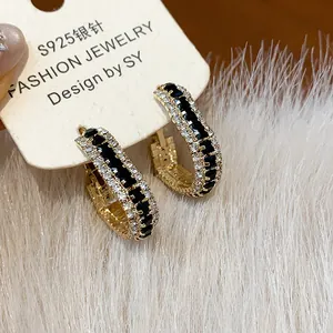 Close-up of geometric hoop earrings with black and white zircons on a soft fur background