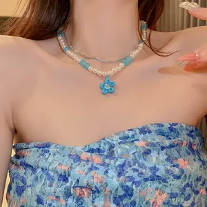 Elegant double-layered pearl necklace with blue beads and a flower pendant on a model