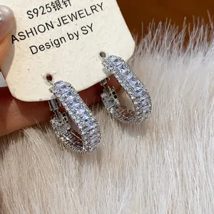 Macro view of luxurious U-shaped hoop earrings with sparkling zircon encrustation