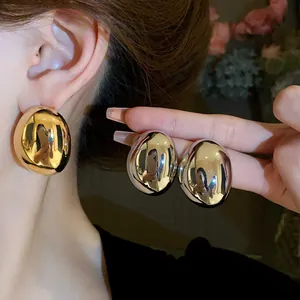 Vista macro detallada de pendientes metálicos ovalados irregulares y minimalistas en oro y plata