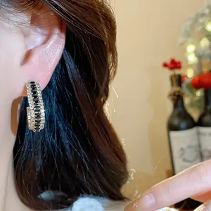 Detail view of luxury C-shaped hoop earrings with black and white cubic zirconia stones
