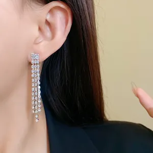 Sparkling silver-tone long tassel dangle earrings with rhinestones worn by a model