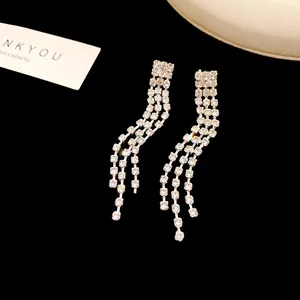 Close-up detail of elegant long silver rhinestone tassel earrings on a black background