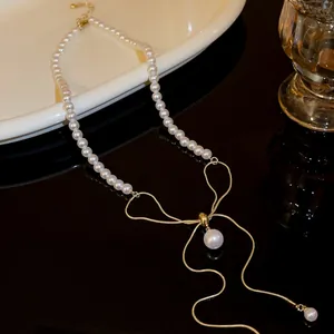 Elegant pearl necklace featuring a gold bow pendant and chain detail, macro view