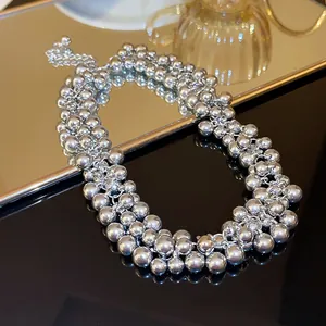 Detailed view of a multi-strand polished silver bead necklace resting on a mirror