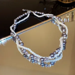 Elegant double-strand pearl necklace featuring white and grey pearls on a reflective surface