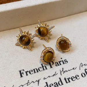 Dettaglio di orecchini a lobo in occhio di tigre placcati oro 18k con accenti di zirconi