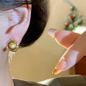 Dettaglio orecchino a perno ovale in occhio di tigre placcato oro 18k elegante