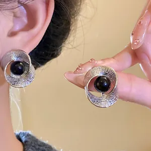 Close-up of silver-tone pleated earrings with a central black bead for an elegant look.