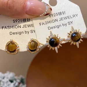 Primo piano di eleganti orecchini occhio di tigre placcati oro 18k con design sole zirconi