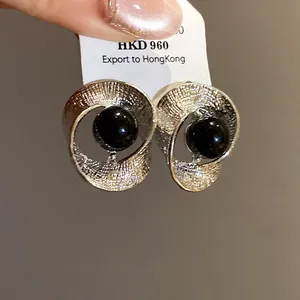 Close-up of elegant silver twisted hoop earrings featuring a glossy black bead center
