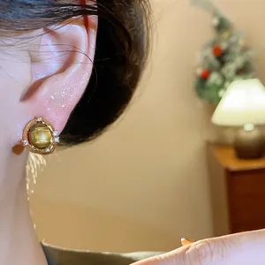 Primo piano di elegante orecchino occhio di tigre placcato oro 18k con zirconi all'orecchio