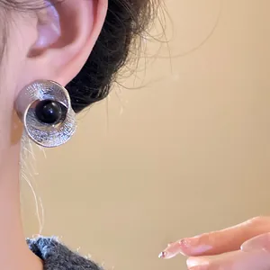 Close-up detail of twisted silver pleated stud earring with a black bead on ear