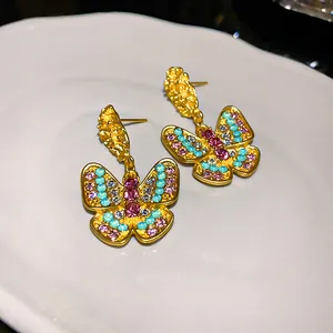 Vintage-style butterfly drop earrings with colorful rhinestones on a white plate
