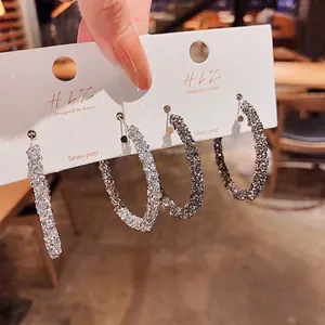 Eleganti orecchini a cerchio glitterati con perni in argento e trama scintillante