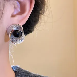Detailed close-up view of a twisted ruffled silver stud earring with a black center bead on a model
