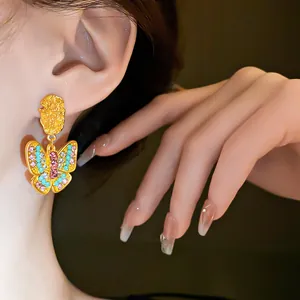 Close-up detail of gold butterfly dangle earrings with colorful pink and blue rhinestones
