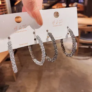 Primo piano di orecchini a cerchio scintillanti con perni in argento.