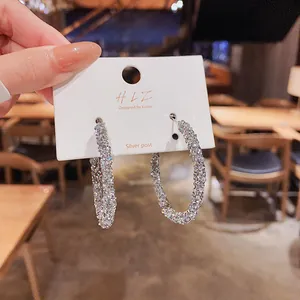 Primo piano di orecchini a cerchio con cristalli scintillanti su cartoncino silver post