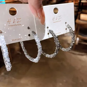 Primo piano di orecchini a cerchio scintillanti con texture in pietra nei toni argento e grigio