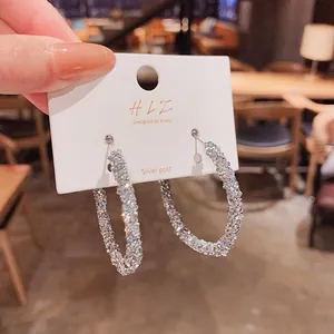 Dettaglio di orecchini a cerchio argento scintillante con perno in argento su cartoncino.