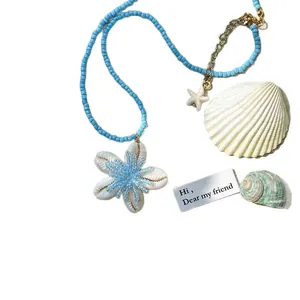 Sommerliche Strandkette aus natürlichen Muscheln mit blauen Perlen und Blumenanhänger