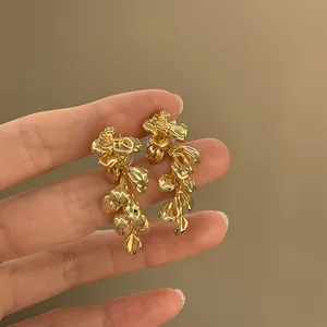 Detailed view of fashionable gold-tone crumpled metal petal tassel drop earrings with silver needle.