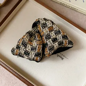 Close-up detail of a triangular tweed hair claw clip with elegant gold and black weaving
