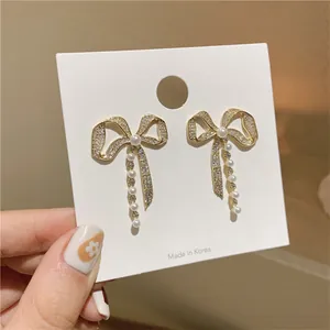 Detailed view of elegant bowknot earrings with pearls and shimmering rhinestones